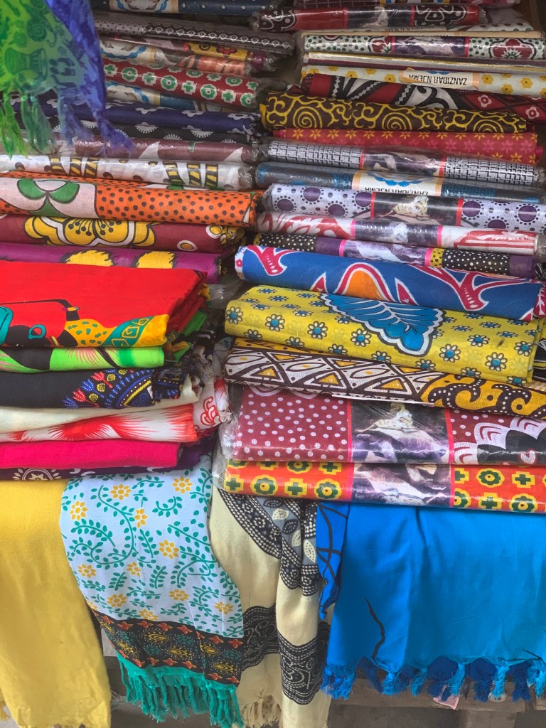 stack of fabrics in the market in stone town by sarah ambitious 